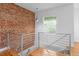 Loft space with exposed brick, modern railings, hardwood floors and a window with natural light at 1211 E 26Th Ave, Denver, CO 80205