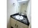Bathroom featuring black marble countertop, white sink and cabinets, and decorative mirror at 56 S Nome St, Aurora, CO 80012