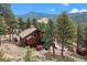 Stunning mountain home with a spacious deck, red umbrella, and lush green trees at 7282 Silverhorn Dr, Evergreen, CO 80439