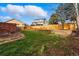 Large grassy backyard bordered by a wooden fence, mature trees and brick grill at 4014 S Kirk Way, Aurora, CO 80013