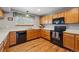Functional kitchen featuring a black range, wood cabinets, and durable wood flooring at 4014 S Kirk Way, Aurora, CO 80013