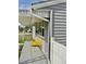 A close-up view of the gray home's porch showcasing a vibrant yellow bench and decorative white awning at 98 N 12Th Ave, Brighton, CO 80601