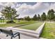 Community bocce ball court with lush green field and seating area, surrounded by mature trees and landscaping at 6220 Salvia St, Arvada, CO 80403