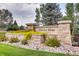 Stone community sign for Sunrise Ridge with lush landscaping and verdant green grass at 6220 Salvia St, Arvada, CO 80403