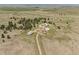 Aerial view of the property featuring several buildings, trees, and expansive fields at 30999 Kootney St, Elizabeth, CO 80107