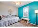 Bright bedroom with turquoise accent wall, ceiling fan and natural light from the window at 6445 Second St, Louviers, CO 80131