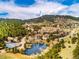 Breathtaking aerial shot of a community with a serene pond, tennis courts, lush trees, and rolling hills at 23612 Pondview Pl # A, Golden, CO 80401
