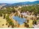 High-angle view of a community with a beautiful pond, tennis courts, and winding roads surrounded by lush greenery at 23612 Pondview Pl # A, Golden, CO 80401