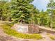 Stone entrance sign 'The Village at Genesee' surrounded by pine trees and green shrubbery at 23612 Pondview Pl # A, Golden, CO 80401