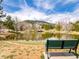 Inviting view of a pond with a reflective surface, a park bench, and greenery with mountain views in the background at 23612 Pondview Pl # A, Golden, CO 80401