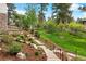 Lush backyard with landscaped stone pathways and mature trees, creating a private outdoor oasis at 646 Ruby Trust Dr, Castle Rock, CO 80108
