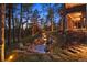 Landscaped backyard featuring a rock water feature, lighting, and mature trees at 646 Ruby Trust Dr, Castle Rock, CO 80108
