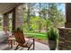 Inviting front porch with stone columns, seating, and view of landscaped yard and lush trees at 646 Ruby Trust Dr, Castle Rock, CO 80108