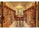 A wine cellar with wooden shelves filled with wine bottles and a table with chairs in the center of the room at 2941 Castle Butte Drive Dr, Castle Rock, CO 80109