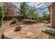 Stone backyard patio features lush landscaping, mature trees, and inviting fire pit for relaxing outdoor evenings at 2908 Open Sky Way, Castle Rock, CO 80109