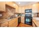 Kitchen with double sink, wood cabinets, tile countertops and black appliances at 911 Snowberry St, Longmont, CO 80503