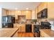 Updated kitchen featuring wood cabinets, tile countertops, and black appliances at 911 Snowberry St, Longmont, CO 80503