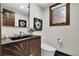 Chic powder room with modern vanity, dark countertop, and decorative accents, with a unique lighting fixture at 8782 S Ault Ln, Morrison, CO 80465