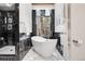 A luxurious bathroom features a modern tub, black marble accents, and forest views through a large window at 8782 S Ault Ln, Morrison, CO 80465