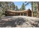 Ranch home with a gravel driveway and a two-car garage in a wooded setting at 8782 S Ault Ln, Morrison, CO 80465