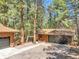 Two car garage with adjacent one car garage, both clad in wood with dark green doors at 8782 S Ault Ln, Morrison, CO 80465