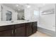 Bathroom featuring double vanity with dark cabinets, bright tile floors and large mirrors at 13328 Xanthia St, Thornton, CO 80602