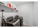 Laundry room featuring modern front load washer and dryer with storage shelf, and white walls at 1172 Elbridge Cir, Elizabeth, CO 80107