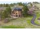 Aerial view of the home, highlighting the back deck, stone accents, and the surrounding wooded landscape at 7465 Kelty Trl, Franktown, CO 80116