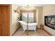 Elegant bathroom with a clawfoot tub, chandelier, and scenic views from the window at 7465 Kelty Trl, Franktown, CO 80116