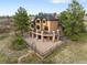 Aerial view of the home with a large back deck, stone pillars, and a fenced-in backyard area at 7465 Kelty Trl, Franktown, CO 80116