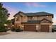 Spacious home exterior with a three-car garage and stone accents, illuminated by outdoor lighting at 7465 Kelty Trl, Franktown, CO 80116
