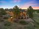 Aerial view of the home at dusk showcasing the back deck with stone pillars and manicured landscaping at 7465 Kelty Trl, Franktown, CO 80116