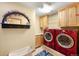 Laundry room with red washer and dryer, wooden cabinets, and decorative accents at 7465 Kelty Trl, Franktown, CO 80116