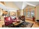 Bright living room with vaulted ceilings, hardwood floors, and a stone fireplace view of the kitchen at 7465 Kelty Trl, Franktown, CO 80116
