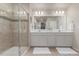 Bathroom featuring a large shower with glass door and double vanity with a large mirror and neutral walls at 1933 Griffin Dr, Brighton, CO 80601
