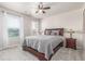 Bedroom with a ceiling fan, two windows with blinds and white curtains, and grey bedding at 1933 Griffin Dr, Brighton, CO 80601