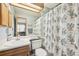 Well-lit bathroom featuring a garden-themed shower curtain, a spacious countertop, and a mirrored wall at 912 S Paris Ct, Aurora, CO 80012