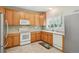 Functional kitchen with wood cabinets, white appliances, a garden window, and tile flooring at 7371 S Mobile St, Aurora, CO 80016