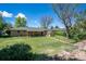 Large backyard with a covered patio, garden shed, lush greenery, and mature shade trees at 2744 S Newton Way, Denver, CO 80236