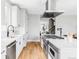 Open kitchen featuring white cabinets, stainless steel appliances, modern lighting, and hardwood floors at 1543 Glencoe St, Denver, CO 80220