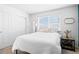 Bright bedroom with a white comforter, bedside table with lamps, and a large window at 4419 N Quatar Ct, Aurora, CO 80019