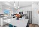 Bright kitchen features stainless steel appliances, gray backsplash, white cabinets and countertops, and island with bar seating at 4419 N Quatar Ct, Aurora, CO 80019