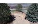 A modern, curved wooden structure with spaces between planks is surrounded by pine trees in this aerial view at 5659 Viewpoint Ave, Firestone, CO 80504