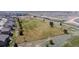 Aerial view of a green field in a neighborhood, with houses on one side, a fence, and distant trees at 5659 Viewpoint Ave, Firestone, CO 80504