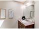 This powder room features a wood vanity with a granite countertop and decorative mirrors and lighting at 8370 E Princeton Ave, Denver, CO 80237