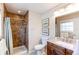 Bright bathroom featuring a tiled shower with a new showerhead, stylish vanity, and granite countertops at 8370 E Princeton Ave, Denver, CO 80237