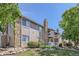 Beautiful condo exterior featuring stone accents, wood siding, a well-manicured lawn, and mature trees at 4400 S Quebec St # D203, Denver, CO 80237