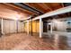 Unfinished basement area features exposed ductwork and support beams with wood-look flooring and doorway to unfinished storage area at 7925 W Layton Ave # 605, Littleton, CO 80123