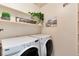Bright laundry room features white washer and dryer, shelf with decorations, and accent artwork at 7925 W Layton Ave # 605, Littleton, CO 80123