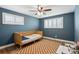 Cozy blue-painted bedroom with shuttered windows, ceiling fan, and wood-style flooring at 8242 E Briarwood Pl, Centennial, CO 80112